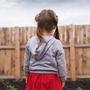 Girl in backyard look at fence